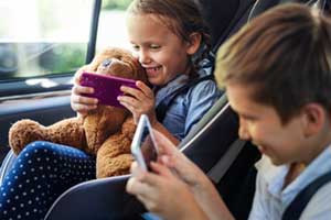 Kinder spielen am Smartphone im PKW